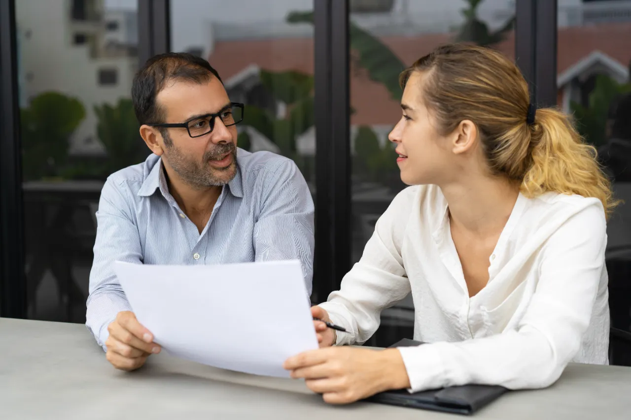 Dono de empresa e responsável administrativo revisando a proposta de seguro de vida em grupo sobre a mesa do escritório